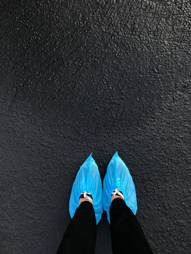 Shoes covered with protective booties on freshly painted asphalt