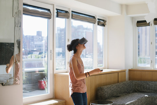 Young woman playing with virtual reality headset at home