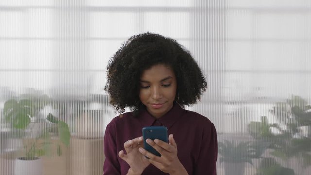 portrait of beautiful african american business intern woman looking pensive texting browsing using smartphone in office workplace background