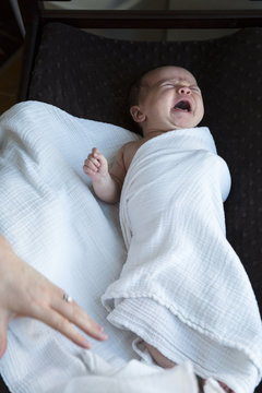 Mother swaddles crying baby