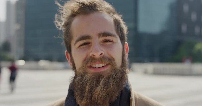 close up portrait professional young hipster man smiling enjoying successful urban lifestyle happy bearded entrepreneur in sunny outdoors city slow motion