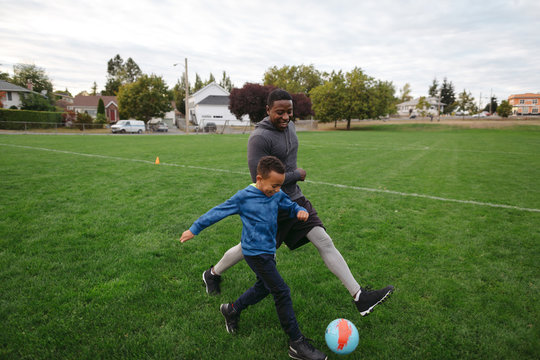 Fototapeta Man and child (father son) playing soccer (football) together in