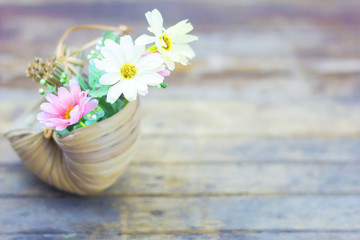 Flowers in a basket on a wooden table.