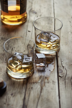 Two Glasses Of Single Malt Scottish Whisky With Ice On A Wooden Table.