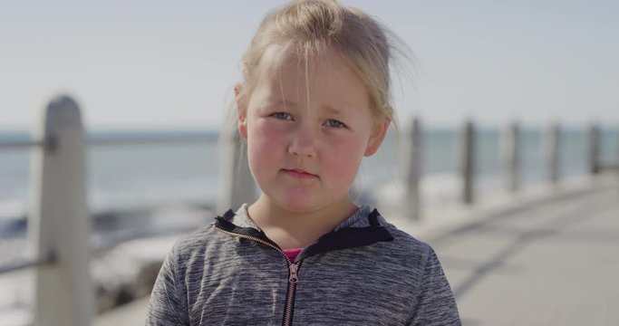 portrait blonde little girl looking unhappy sad caucasian kid grumpy on warm summer day seaside beach