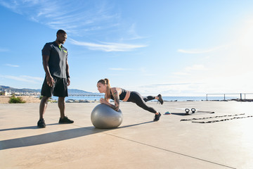 Woman with trainer working out on beach