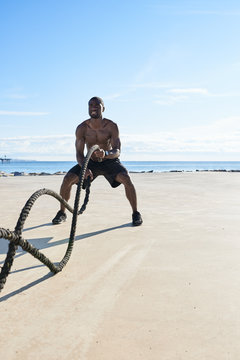 Muscular man training with ropes