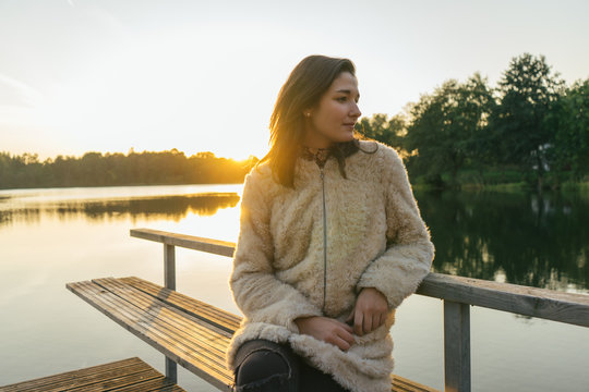 Girl on a Dock's Lake at Sunset.