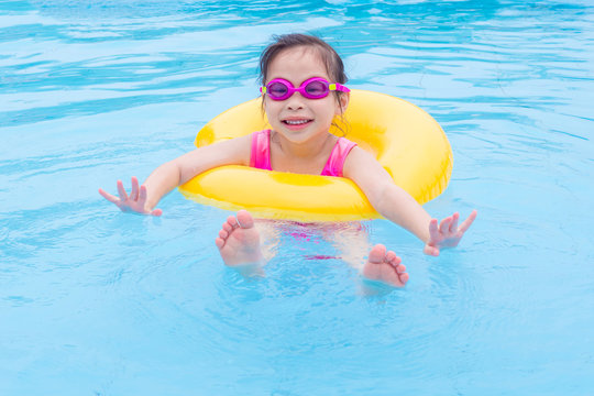 Little asian girl swimming with ring in the pool