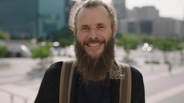close up portrait of cheerful mature hippie man smiling happy in sunny urban city enjoying travel lifestyle 