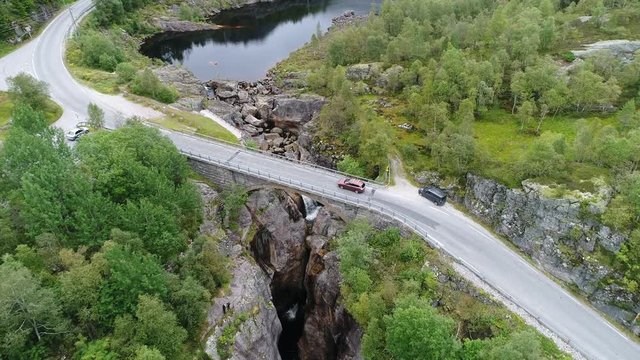 Aerial Footage of a Car crossing a stone bridge over a small waterfall