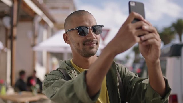 portrait of attractive young man wearing sunglasses taking photo using phone