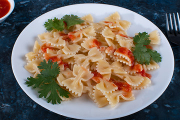 Cooked pasta with tomato sauce and greens.