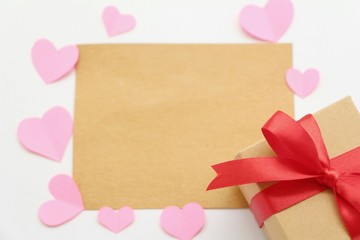 Brown blank card with paper heart shaped and gift box on white background,flat lay.