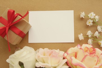 White blank greeting card with gift box red ribbon and flower,flat lay.
