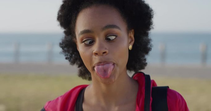 portrait cute young african american woman making faces enjoying crazy fun on summer vacation day seaside background wearing sporty fashion