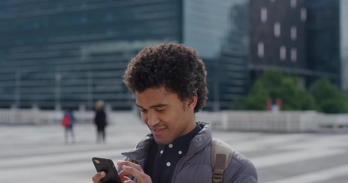 portrait young mixed race businessman using smartphone in city texting browsing online messages on mobile phone enjoying professional urban lifestyle slow motion