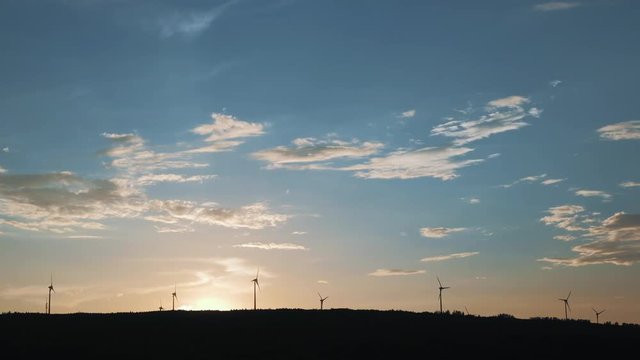 Wind energy turbines silhouette at sunset, renewable electric energy source. Beautiful background image taken at sunset in 4K UHD