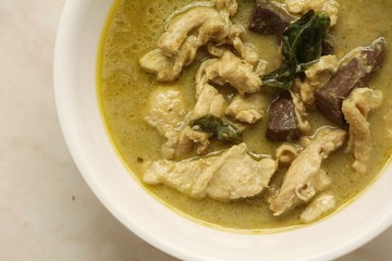 Green curry with chicken in dish on marble table.