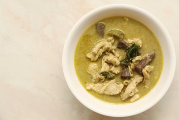 Green curry with chicken in dish on marble table.