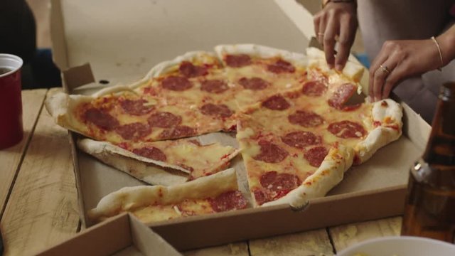 slow motion group of multi ethnic friends eating pizza meal together on weekend gathering celebration