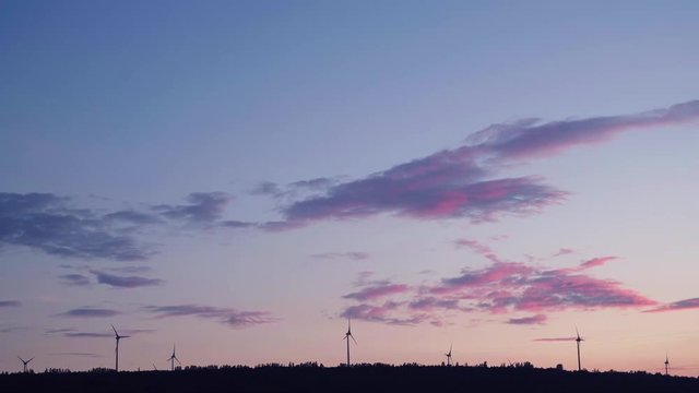 Wind energy turbines silhouette at sunset, renewable electric energy source. Beautiful background image taken at sunset in 4K UHD
