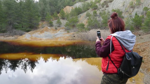 Woman uses her cell phone to take photos of Red Lake Mitsero in Cyprus