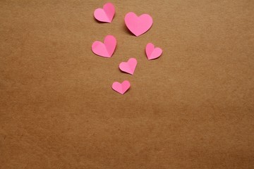 Pink paper cut of mini heart on brown background,love valentine concept, minimal flat lay.