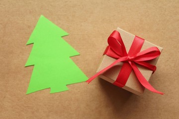Gift box with paper cut of Christmas tree on brown background,flat lay.