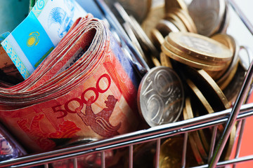 Tenge. Kazakhstan money in shopping cart on red background close up..
