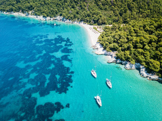 Three sailing boats anchored near the private beach on the island of Skopelos in Greece. View from above at Kastani beach - obrazy, fototapety, plakaty
