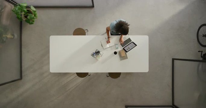young african american business woman working late writing notes brainstorming ideas using laptop browsing online dedicated employee in modern office workplace top view