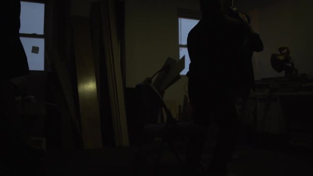 3 men fighting in a dark room.