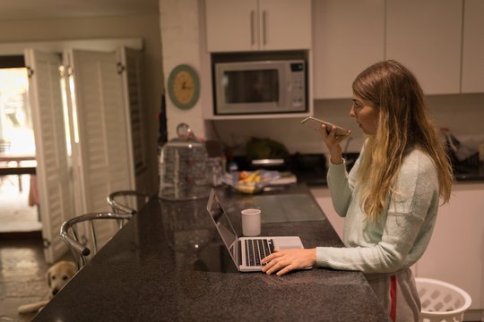 Girl taking on mobile phone while using laptop