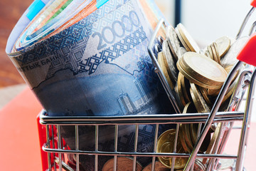 Tenge. Kazakhstan money in shopping cart on red background close up..
