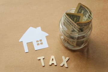 Paper cut of house with money in jar,text tax wood.