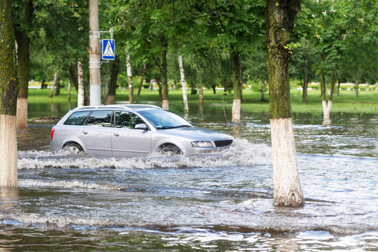 The car, moving on a flooded road in the city