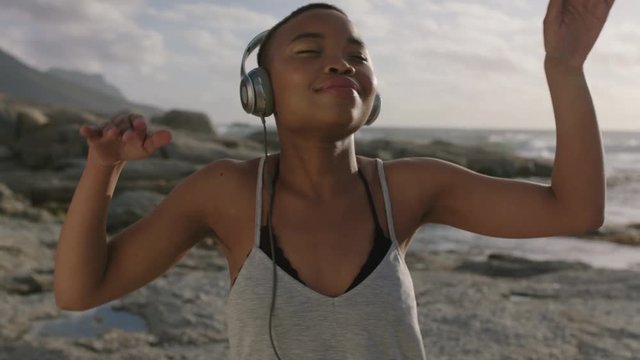 young attractive african american woman wearing headphones listening to music dancing happy at beach