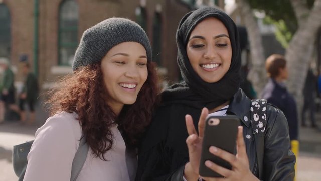 portrait of two young woman friends close up of multi ethnic girlfriends posing making faces taking selfie photo using smartphone