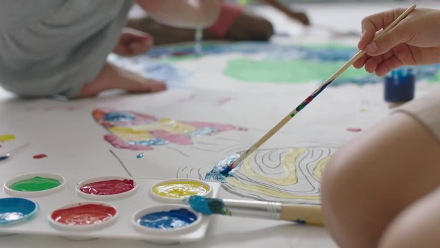 close up multi ethnic children paint colorful space pictures together on paper using paint brushes happy kids enjoying fun creativity painting science fiction color palette
