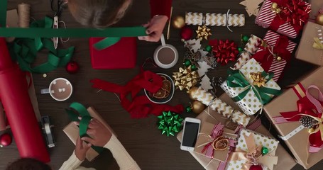 close up time lapse of two young women wrapping christmas gifts using vibrant colorful paper multi ethnic friends wrap presents festive decorations celebration - Powered by Adobe