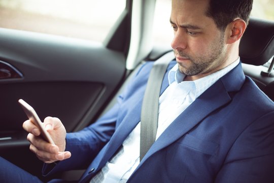 Businessman using mobile phone in a car