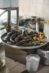 Typical Colombian large black morcilla blood sausages sizzling in a pan on a street food market stall in Cali