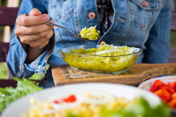 Woman eats fresh green grated cucumber salad with garlic and onion in glass bowl. Very juicy and light. Hands holds summer salad. Organic farm food. Raw lunch or vegan dinner. Vegetarian healthy food
