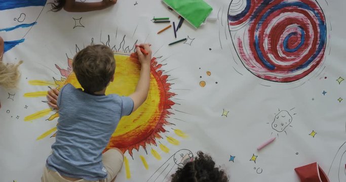 young diverse children paint colorful space pictures together on paper using paint brushes happy kids enjoying fun creativity painting science fiction space drawing pictures top view