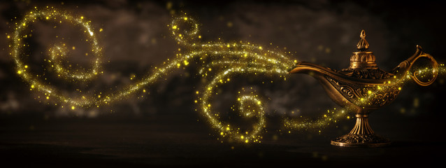 Image of magical mysterious aladdin lamp with glitter sparkle smoke over black background. Lamp of...