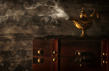 Image of magical mysterious aladdin lamp with smoke over black background. Lamp of wishes.