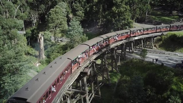 Hovering above Puffing Billy as it travels over the Trestle Bridge in Belgrave with people looking out of the train windows