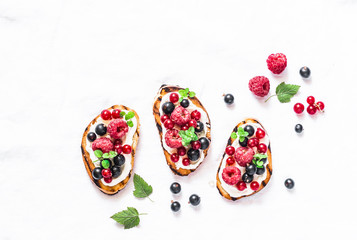 Berries bruschetta on a light background, top view. Sandwiches with cream cheese, raspberries, red...