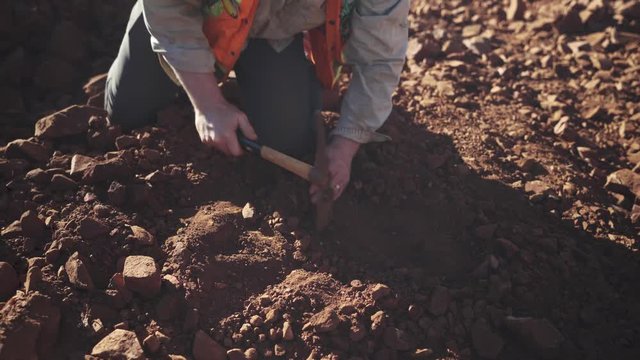 Metal Detector being held over exposed rocks by a geologist to look for gold